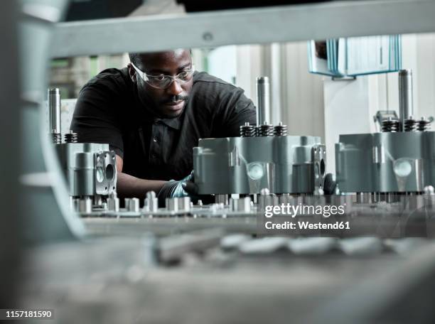 young man checking production line on a conveyor belt - metaalwerker stockfoto's en -beelden