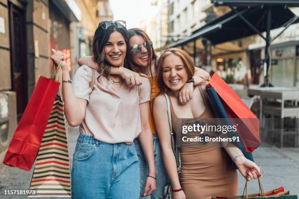girls with shopping bags hugging - girl after shopping stock pictures, royalty-free photos & images