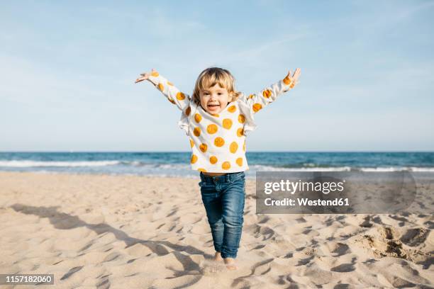 portrait of happy little girl running on the beach - child arms up stock pictures, royalty-free photos & images