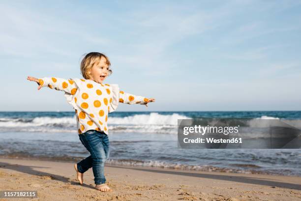 happy little girl running barefoot on the beach - happy toddler stockfoto's en -beelden