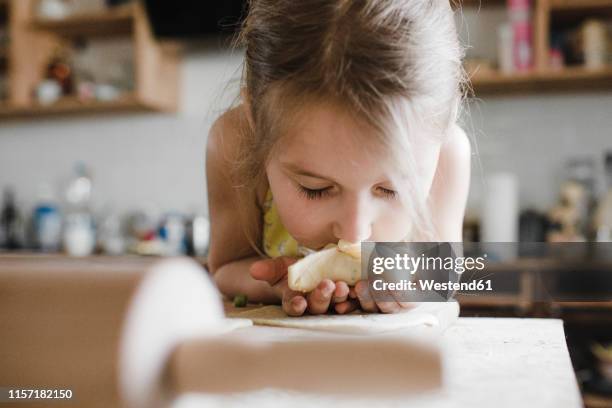 little girl smelling freshly prepared stuffed pastry - human nose stockfoto's en -beelden
