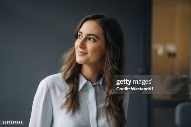 portrait of smiling young businesswoman looking sideways - at a glance foto e immagini stock