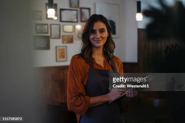 portrait of smiling woman holding clipboard in restaurant - dark clothes stock pictures, royalty-free photos & images