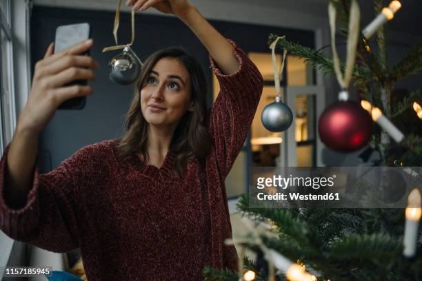 smiling young woman taking a selfie at christmas tree - photo call stock-fotos und bilder