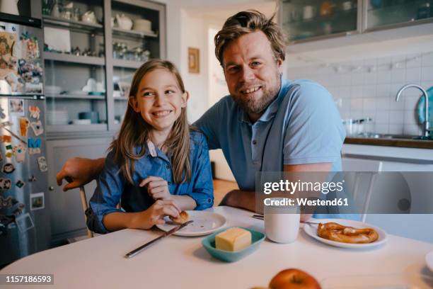 portrait of father and daughter at home sitting at breakfast table - sitting at table looking at camera stock-fotos und bilder