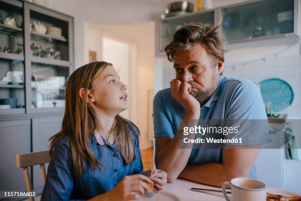 daughter talking to father in kitchen at home - niños pensando fotografías e imágenes de stock