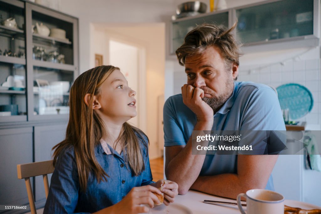 Daughter talking to father in kitchen at home