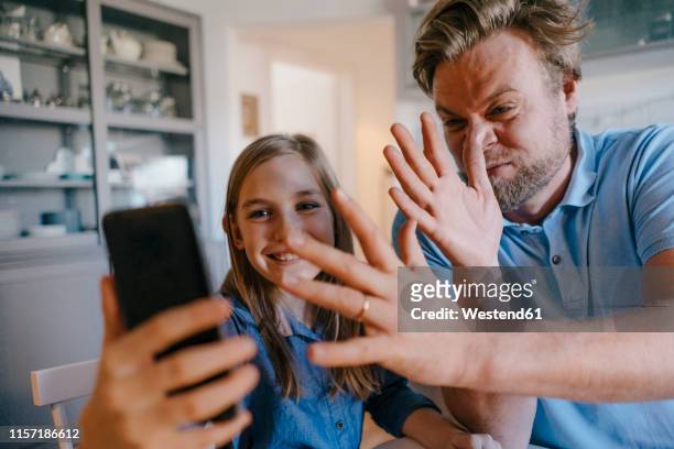 Playful father and daughter taking a selfie at home