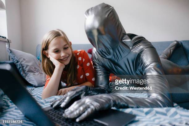 man in morphsuit and girl lying on couch at home using laptop - crazy man computer stock pictures, royalty-free photos & images