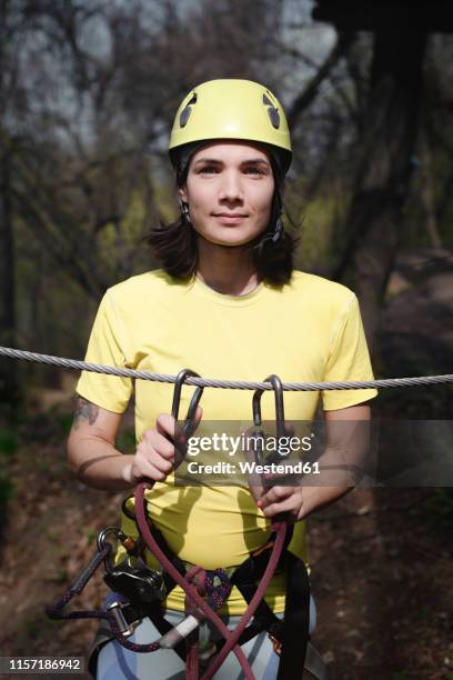 young woman wearing yellow t-shirt and helmet in a rope course - zekeren stockfoto's en -beelden