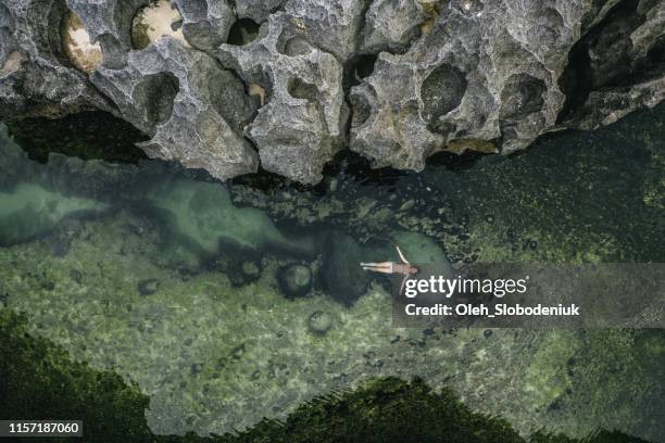 malerische luftaufnahme der frau, die auf dem wasser in angel es billabong, nusa penida schwimmt - nusa penida stock-fotos und bilder