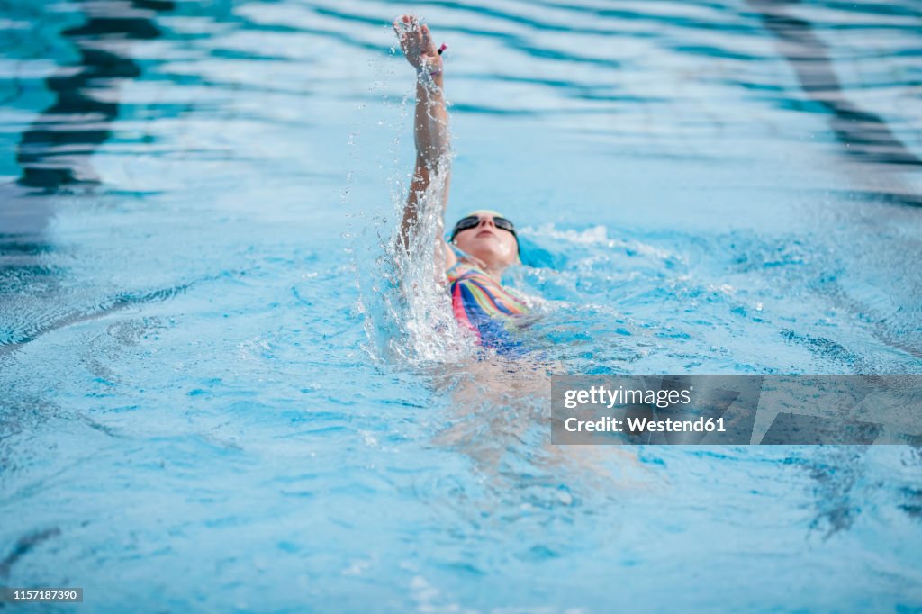 Young woman swimming in swimming pool, backstroke