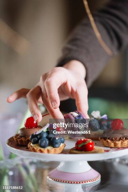 woman's hand arranging macaron on cake stand, close-up - feeling full stock pictures, royalty-free photos & images