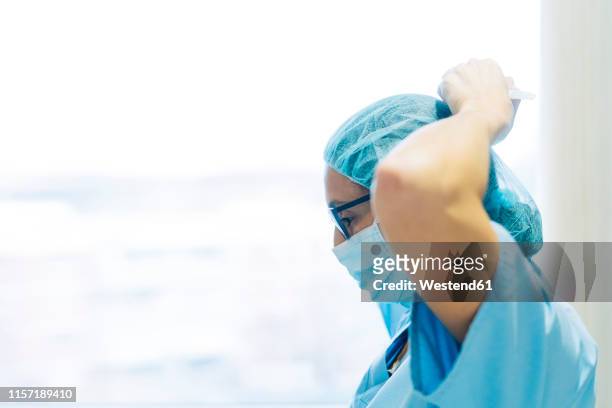 female doctor tying surgical mask, preparing for surgery - protective face mask side stock pictures, royalty-free photos & images