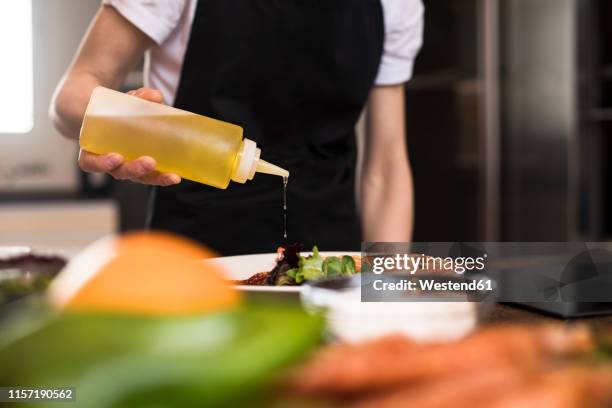 close-up of woman cooking in kitchen pouring olive oil on a dish - flutters photos et images de collection