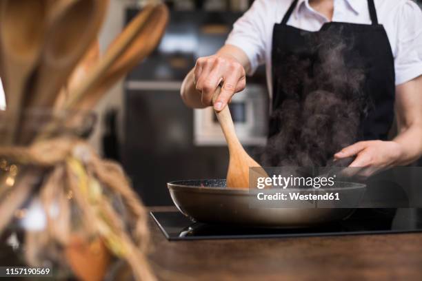 close-up of woman cooking in kitchen using a pan - close up cooking stock-fotos und bilder