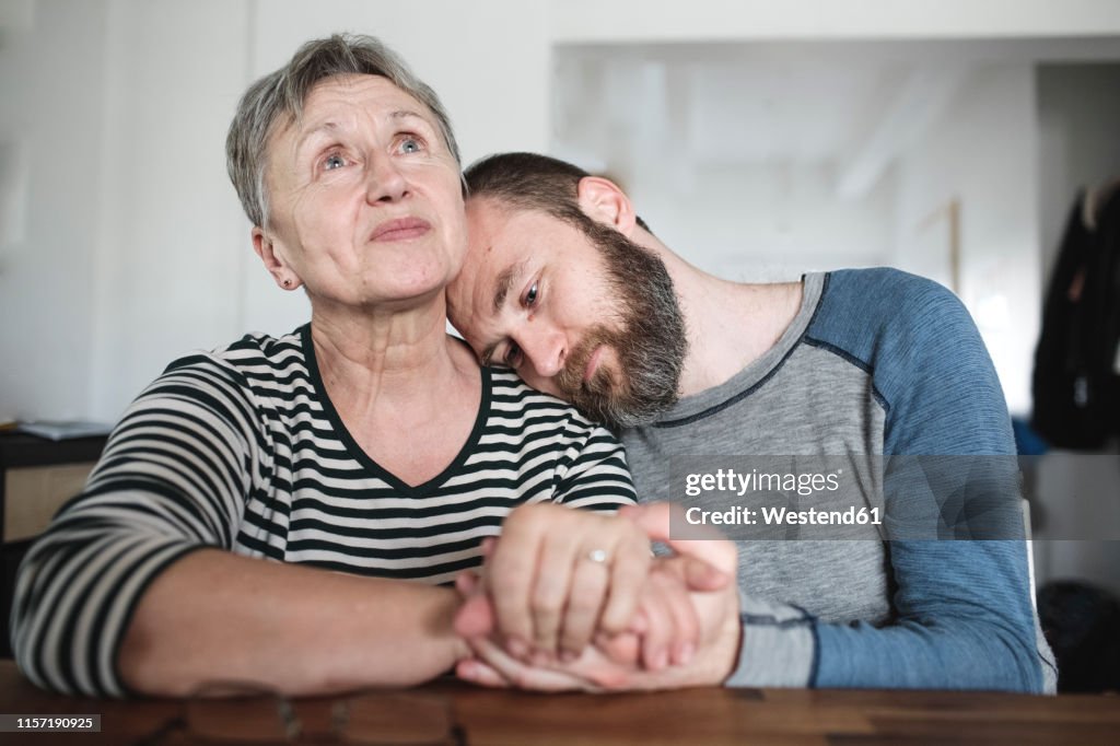 Affectionate adult son with senior mother at home