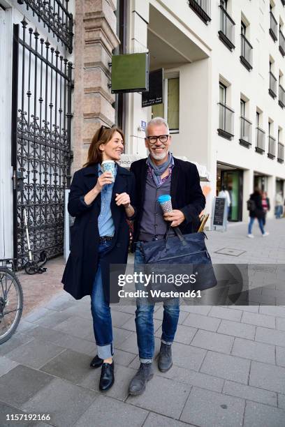 smiling mature couple with reusable bamboo cups walking in the city - munich food stock pictures, royalty-free photos & images
