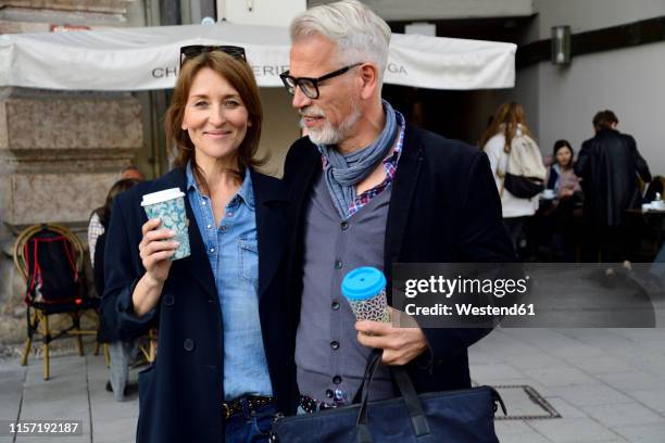 portrait of smiling mature couple with reusable bamboo cups in the city - couple in cafe man beard coffee stock-fotos und bilder