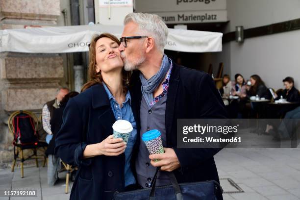 mature couple with reusable bamboo cups kissing in the city - viktualienmarkt stock-fotos und bilder