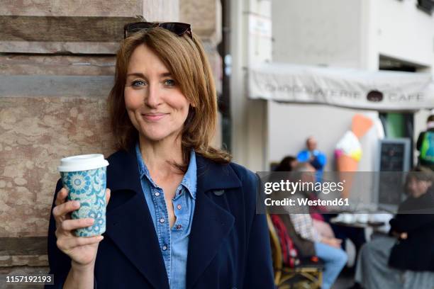 portrait of smiling mature woman with reusable bamboo cup in the city - cup portraits foto e immagini stock