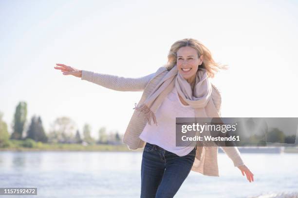 carefree mature woman at the riverside - woman in a shawl stock-fotos und bilder