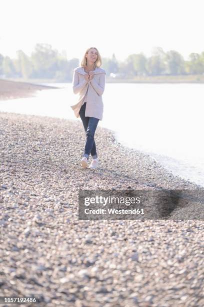 happy mature woman walking at the riverside - summer cardigan women stockfoto's en -beelden