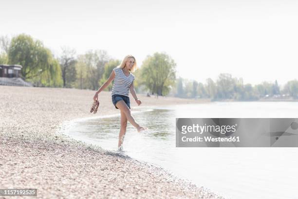 carefree mature woman splashing in a river - mature woman in water stock pictures, royalty-free photos & images