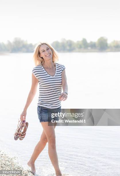 smiling mature woman wading in a river - ladies shorts stockfoto's en -beelden