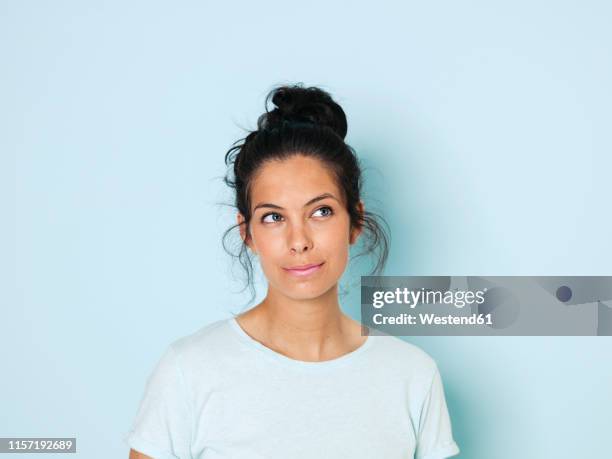 portrait of young woman with black hair, light blue background - hair bun stock pictures, royalty-free photos & images