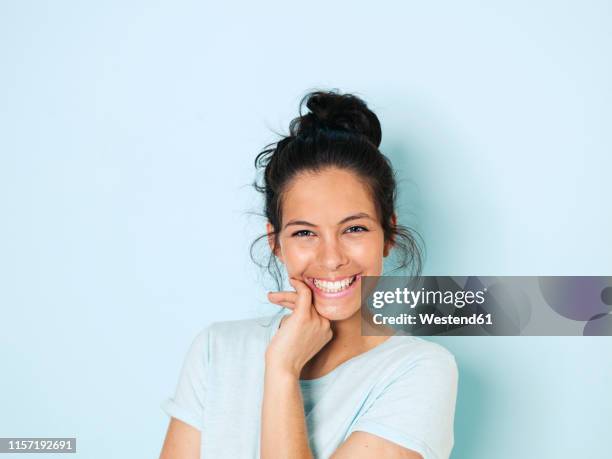 portrait of young woman with black hair, light blue background - chignon fotografías e imágenes de stock