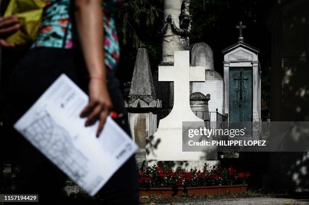 Tourist holding a map of the Pere Lachaise cemetery walks past a tomb during her visit at the cemetery in Paris on July 22, 2019.