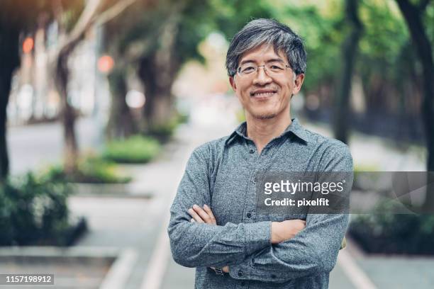 mid age chinese ethnicity man in the park - chinese ethnicity stock pictures, royalty-free photos & images