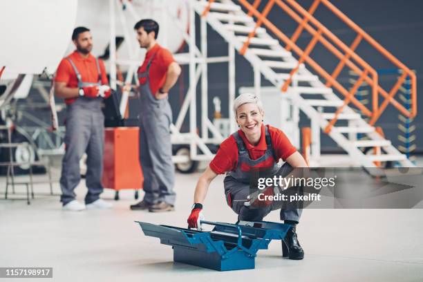 lächelnde technikerin arbeitet im hangar - flugzeugmechaniker stock-fotos und bilder