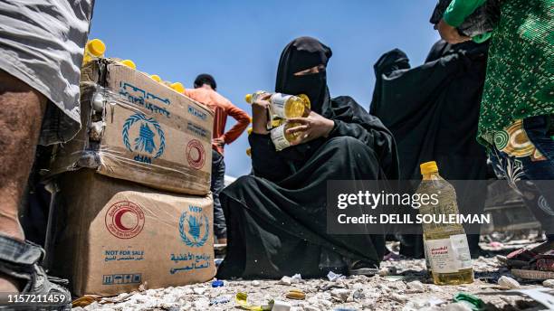 Woman wearing a niqab holds bottles of sunflower oil distributed as part of food aid at al-Hol camp for displaced people in al-Hasakeh governorate in...