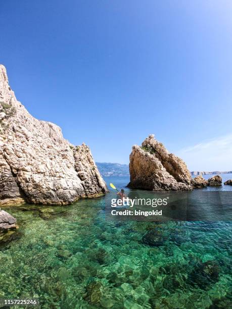 woman paddling between rocks - croazia stock pictures, royalty-free photos & images