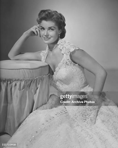 Esther Williams, US swimmer and actress, wearing a lacy flowered gown, leaning on a chair, USA, circa 1945.