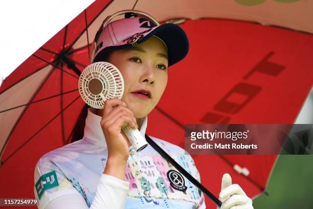 Rei Matsuda of Japan uses a portable fan during the first round of the Nichirei Ladies at Sodegaura Country Club Shinsode Course on June 21, 2019 in...