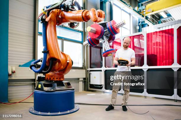 industrie 4.0: junger ingenieur arbeitet an einem roboterarm - roboterarm stock-fotos und bilder