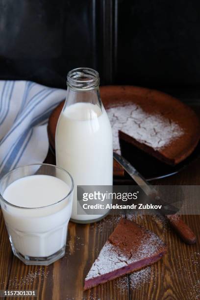 fresh milk in a glass bottle and glass, next to a pie, sprinkled with powdered sugar, against a wooden table. the concept of healthy organic products. rustic still life style. place for text. - sugar jar stock pictures, royalty-free photos & images