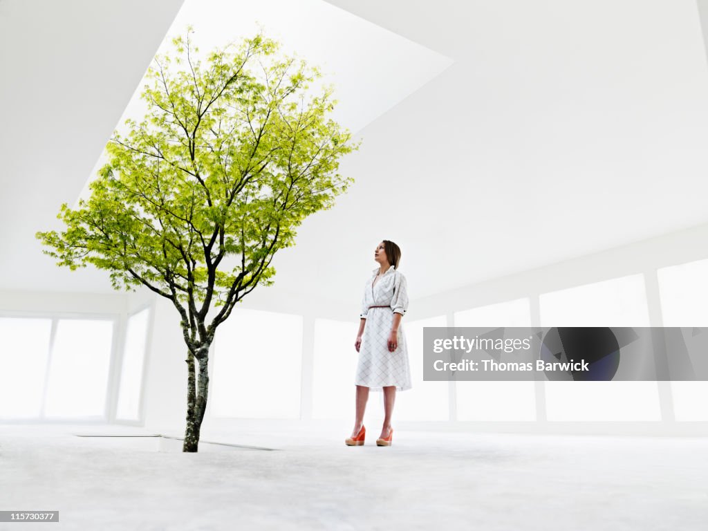 Woman looking up at tree growing out of stairwell