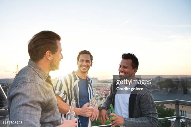three young men with beer on the roof - male friends drinking beer stock pictures, royalty-free photos & images
