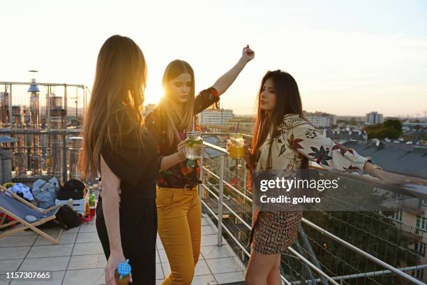 tres mujeres jóvenes bebiendo cócteles al aire libre - cóctel fiesta fotografías e imágenes de stock