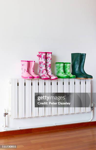 family of wellington boots on radiator - rubber boots stock pictures, royalty-free photos & images