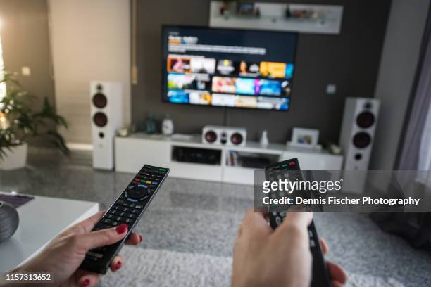 man and woman with television remote control - couple watching movie ストックフォトと画像