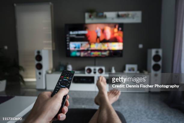 remote control with television in living room - mirar un objeto fotografías e imágenes de stock