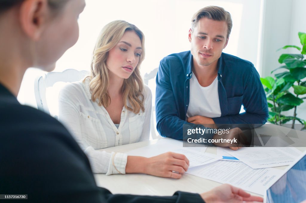 Verzekeringsagent met echtpaar op zoek door documenten.