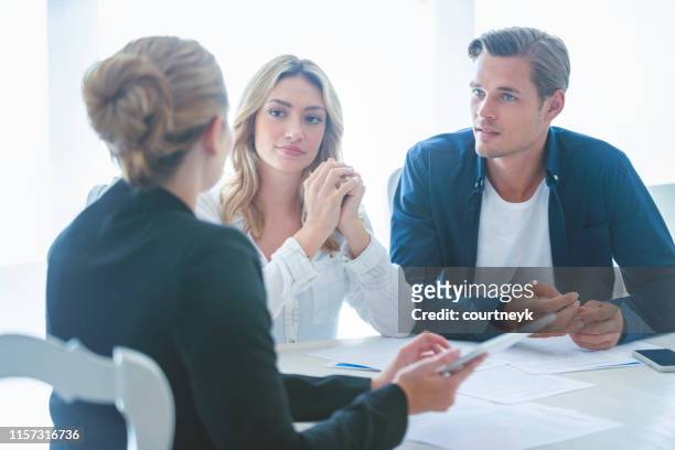 real estate agent with couple looking through documents. - stern form stock pictures, royalty-free photos & images