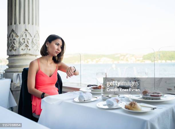 uitgeputte vrouw wacht haar datum, het controleren van de tijd in het restaurant - ongeduldig stockfoto's en -beelden