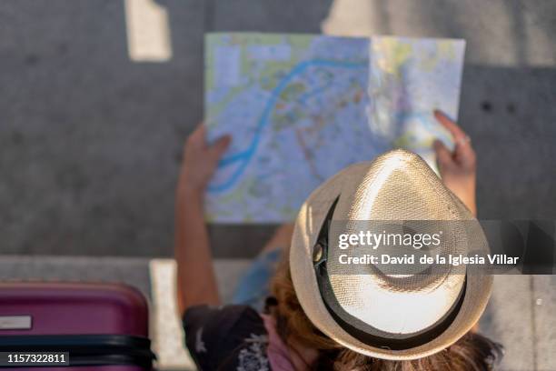 young woman wearing a hat consulting a map - destination de voyage 個照片及圖片檔